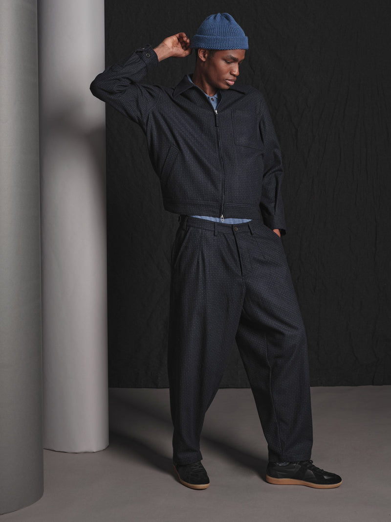 Person wearing a dark outfit with a blue cap against a black background
