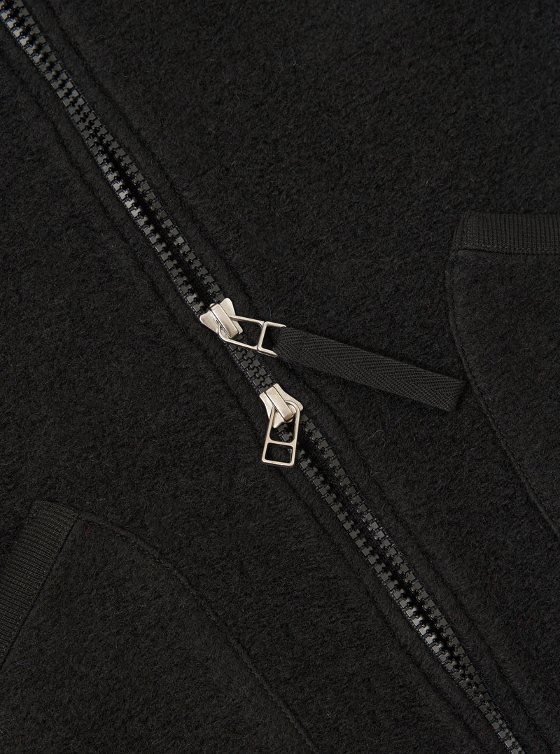 Rear view of the Universal Works Black Wool Fleece Zip Waistcoat presented against a clean white background. The back panel highlights the soft wool fleece texture, clean seam construction, and jersey-bound hem and armholes.