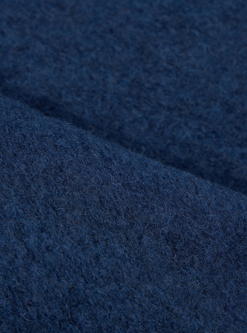 Extreme close-up fabric swatch image showcasing the texture of the Indigo Wool Fleece Zip Waistcoat. The detailed shot highlights the rich indigo blue tone, soft fibers, and cozy tactile feel of the wool fleece material.