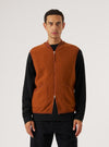 A model showcases the Rust Wool Fleece Zip Waistcoat against a clean white backdrop. The rust-colored wool vest features a zip front and trim.
