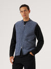 A model poses in a Slate Blue Wool Fleece Zip Waistcoat against a white backdrop. The zip-up waistcoat is wool fleece with a slate blue trim.