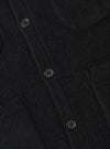 Close-up of the black wool fleece cardigan showing the texture of the fabric and the button details. The background is a plain white surface.