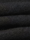 Close-up of a folded Black Wool Fleece Cardigan. The soft, textured material is stacked against a dark background, highlighting the cardigan's cozy feel.