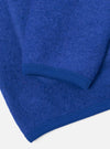 Close-up detail of a blue wool fleece cardigan laid flat on a white surface, showing the lower sleeve and hem. The boiled wool texture is clearly visible. Both the ribbed cuff and ribbed hem trim are shown in matching royal blue, with neat topstitching along the seams.