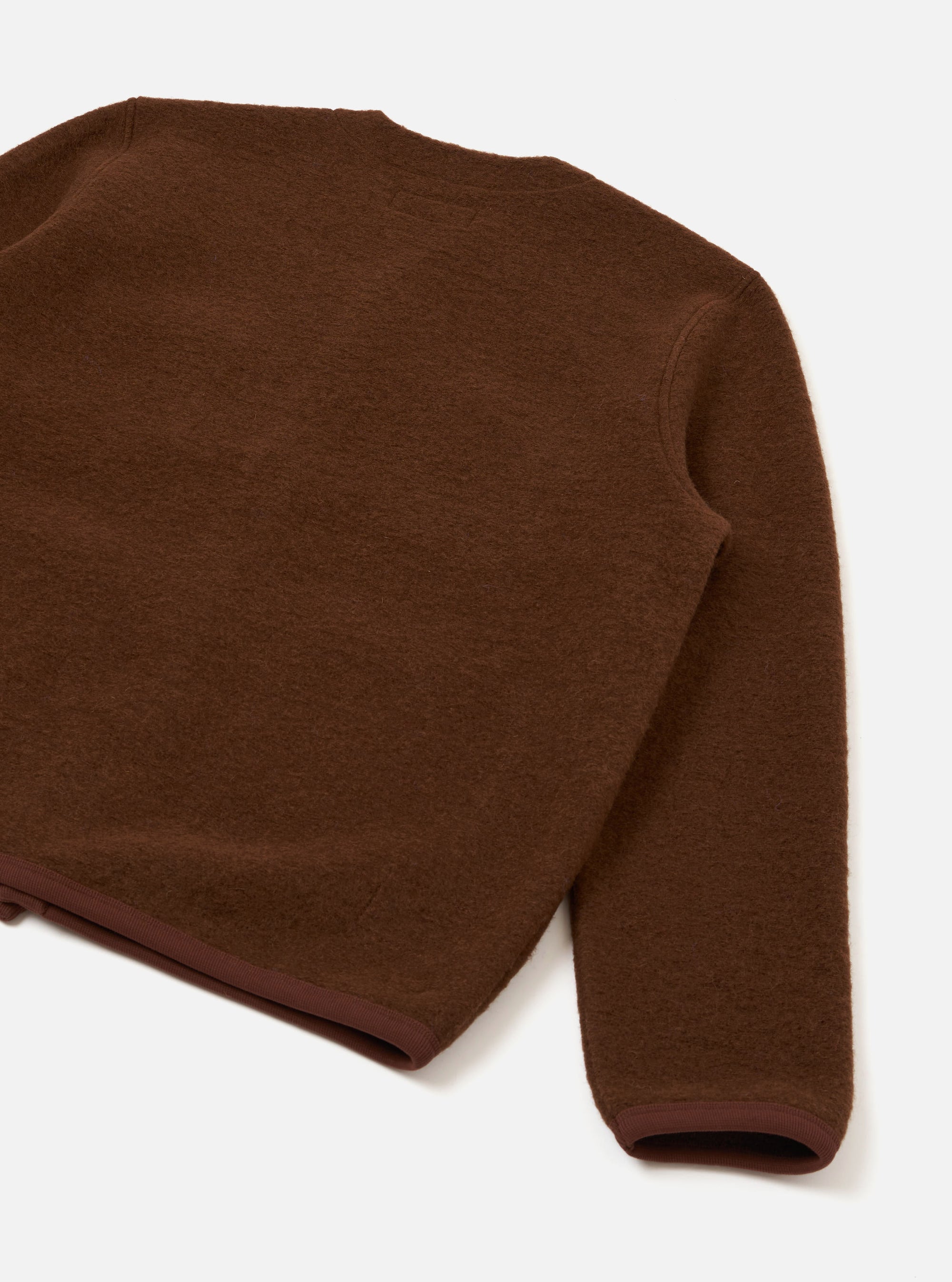 Cacao brown wool fleece cardigan photographed as a flat lay on a white surface. The close-cropped shot shows the back panel and one sleeve. The fabric has a soft, brushed texture. A darker brown ribbed trim is visible at the hem and cuff.