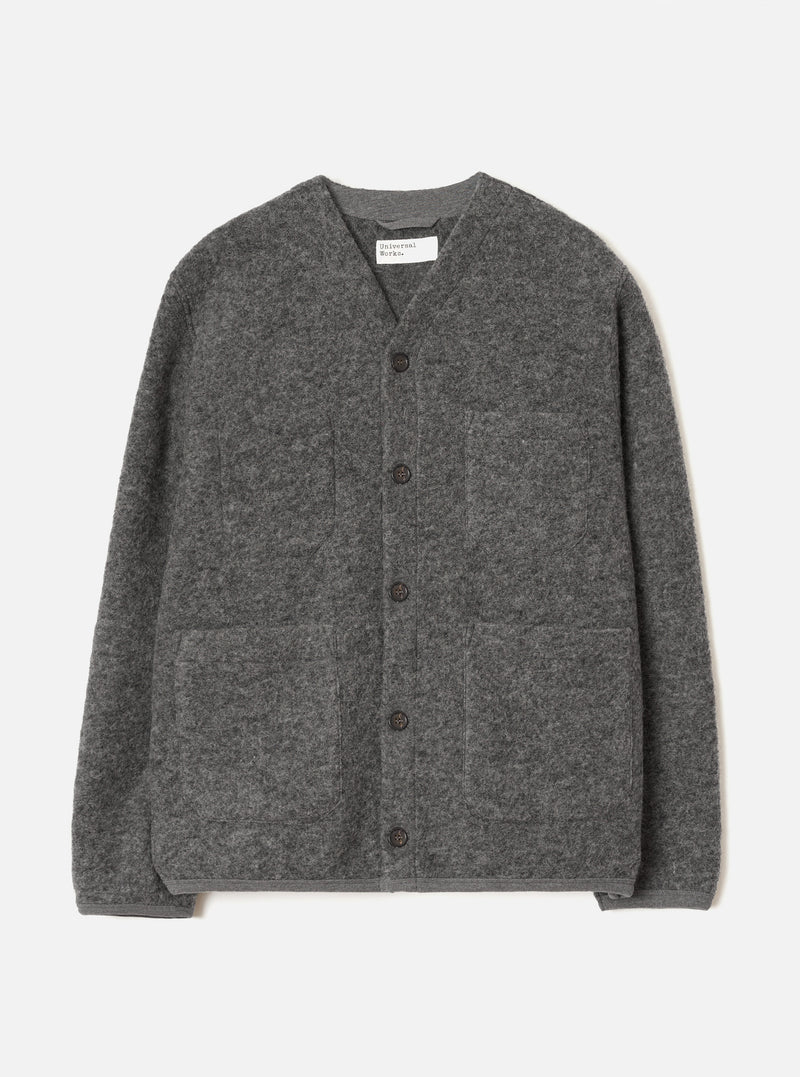 Grey marl wool fleece cardigan laid flat on a light grey seamless backdrop. Collarless V-neckline with a Universal Works woven label at the back neck. Five dark horn buttons down the centre front. Four patch pockets: two chest, two hip. Relaxed fit with long sleeves and a straight hem.
