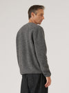 Grey marl wool fleece cardigan worn by a male model, shown from a rear three-quarter angle against a light grey studio backdrop. The brushed, textured fleece fabric has a soft, fluffy surface in a heathered grey tone. Raglan-style shoulder seams are visible. The ribbed hem and cuffs are shown. Cropped at mid-thigh, worn over dark trousers.