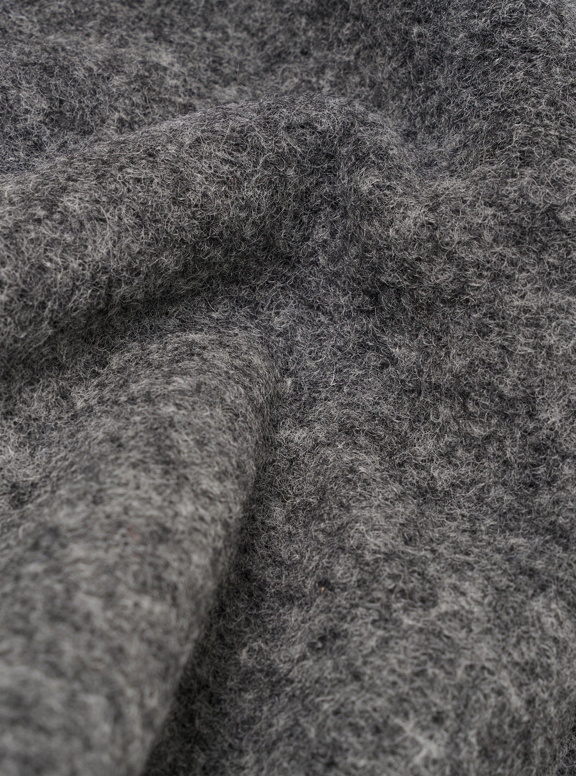 Close-up detail shot of the grey marl wool fleece fabric, showing a heavily textured, brushed surface with visible loose fibres and a deep pile. The image highlights the fluffy texture and tonal variation across the charcoal grey marl knit.