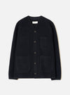 Navy wool fleece cardigan laid flat on a light grey studio backdrop. Collarless V-neckline with a woven brand label at centre back neck. Five dark buttons fasten the front placket. Four large patch pockets sit across the chest and lower front. Finished hem and cuffs in a smoother navy fabric.