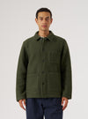 A man stands against a white backdrop wearing an Olive Wool Fleece Field Jacket. The jacket is buttoned and has pockets. He is also wearing navy pants.