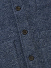 Close-up of the slate blue wool fleece field jacket, showing the texture of the wool and the button details. The jacket is laid flat on a neutral surface.