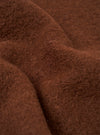 Close-up of the cacao wool fleece fabric used in the zip bomber, showing a dense, brushed texture with visible individual fibres. The rich brown tone is consistent across the frame, with soft folds highlighting the fabric's plush, fluffy surface.