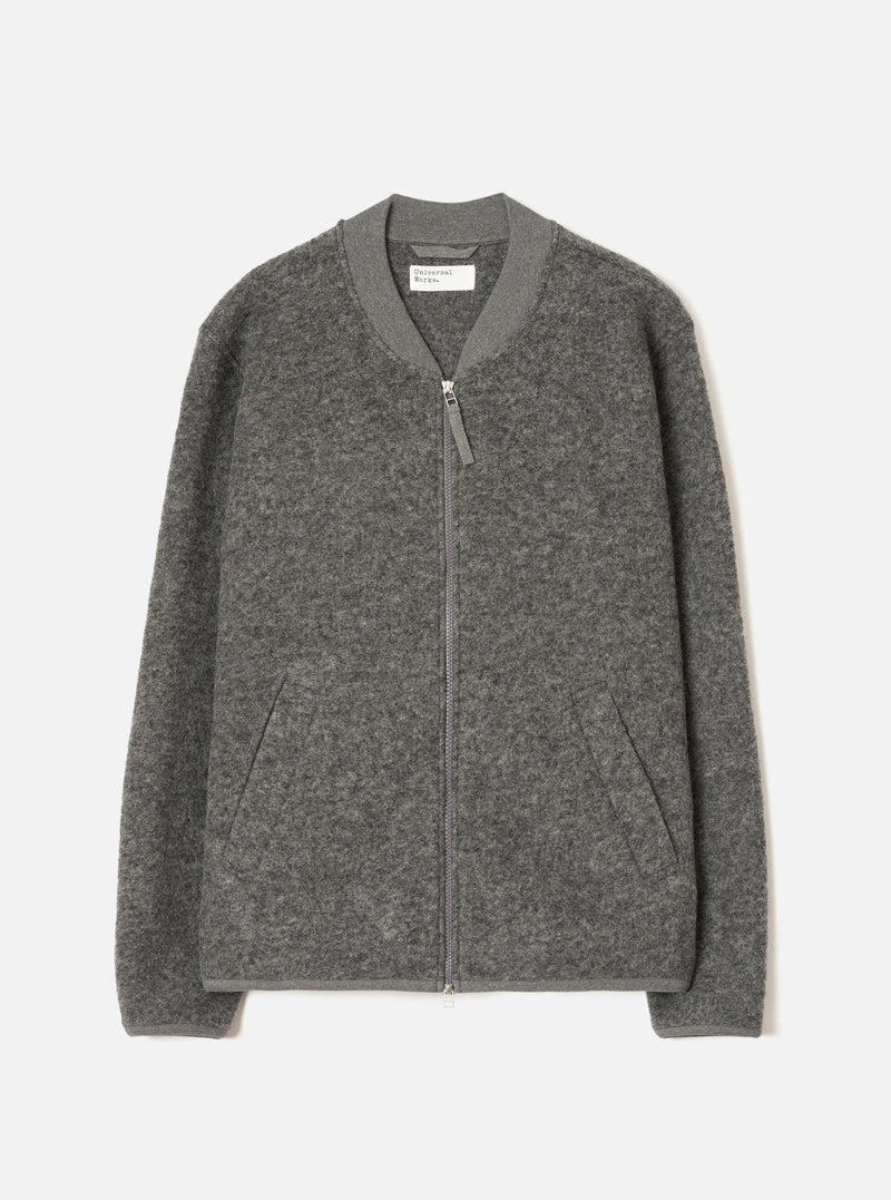 Grey marl wool fleece zip bomber, flat lay on a light grey seamless backdrop. Ribbed bomber collar with a centre-front silver zip and leather zip pull. Two welt hand pockets at the hem. Ribbed cuffs and hem band. Textured boiled wool fleece fabric throughout. Universal Works label visible at the inner collar.
