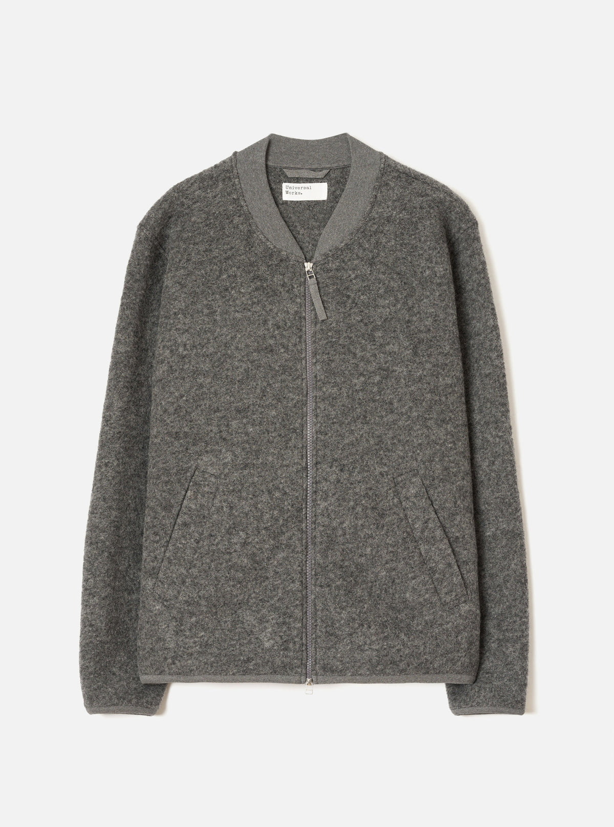 Grey marl wool fleece zip bomber, flat lay on a light grey seamless backdrop. Ribbed bomber collar with a centre-front silver zip and leather zip pull. Two welt hand pockets at the hem. Ribbed cuffs and hem band. Textured boiled wool fleece fabric throughout. Universal Works label visible at the inner collar.