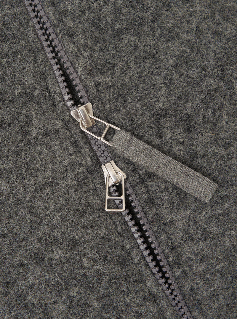 Close-up detail of the grey marl wool fleece zip bomber, showing a two-way gunmetal zip with twin silver-toned sliders and a woven fabric zip garage. The brushed wool fleece texture is visible across the full frame, showing a flecked marl finish.