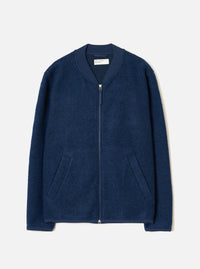 Indigo wool fleece zip bomber laid flat on a light grey studio backdrop. The jacket features a ribbed bomber collar in matching navy fabric, a full-length silver zip, two welt hip pockets, and ribbed cuffs. The boiled wool fleece has a dense, textured surface. A Universal Works woven label is visible at the neck.