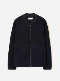 Navy wool fleece zip bomber jacket, flat lay on a light grey seamless backdrop. Textured boiled-wool-style fleece body with a smooth ribbed bomber collar in contrast navy fabric. Full-length silver zip with a small pull tab. Two welt pockets at the hip. Ribbed cuffs and hem. Universal Works woven label visible at the back neck.