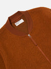 Close-up of the Rust Wool Fleece Zip Bomber on a white background. The rust-colored wool jacket features a zip closure and ribbed collar.