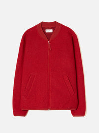Scarlet wool fleece zip bomber laid flat on a white studio backdrop. Boiled wool texture throughout, ribbed bomber collar in tonal satin fabric, centre-front zip with silver teeth and a red leather pull tab. Two welt pockets at the hip, ribbed cuffs and hem. Universal Works woven label visible at the neck.
