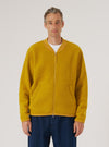 A model poses in a Yellow Wool Fleece Zip Bomber against a white backdrop. The bomber is a vibrant yellow, made of wool fleece, and features a zip closure. The fit is relaxed and casual.
