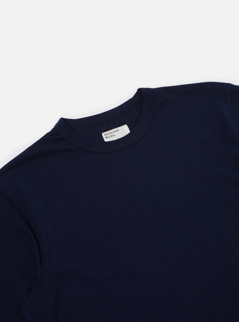 Close-up of the Navy Single Jersey Core Tee on a white surface. The tee is a dark navy color and made of a soft, single jersey material. The fit is relaxed and comfortable.