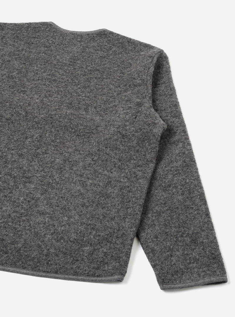 Grey marl wool fleece zip liner jacket, flat lay on a white studio backdrop. Shot shows the back and right sleeve at close range. The boiled wool fleece texture is visible across the body and sleeve. A contrast bound hem runs along the bottom edge. The round neckline is partially visible at the top.