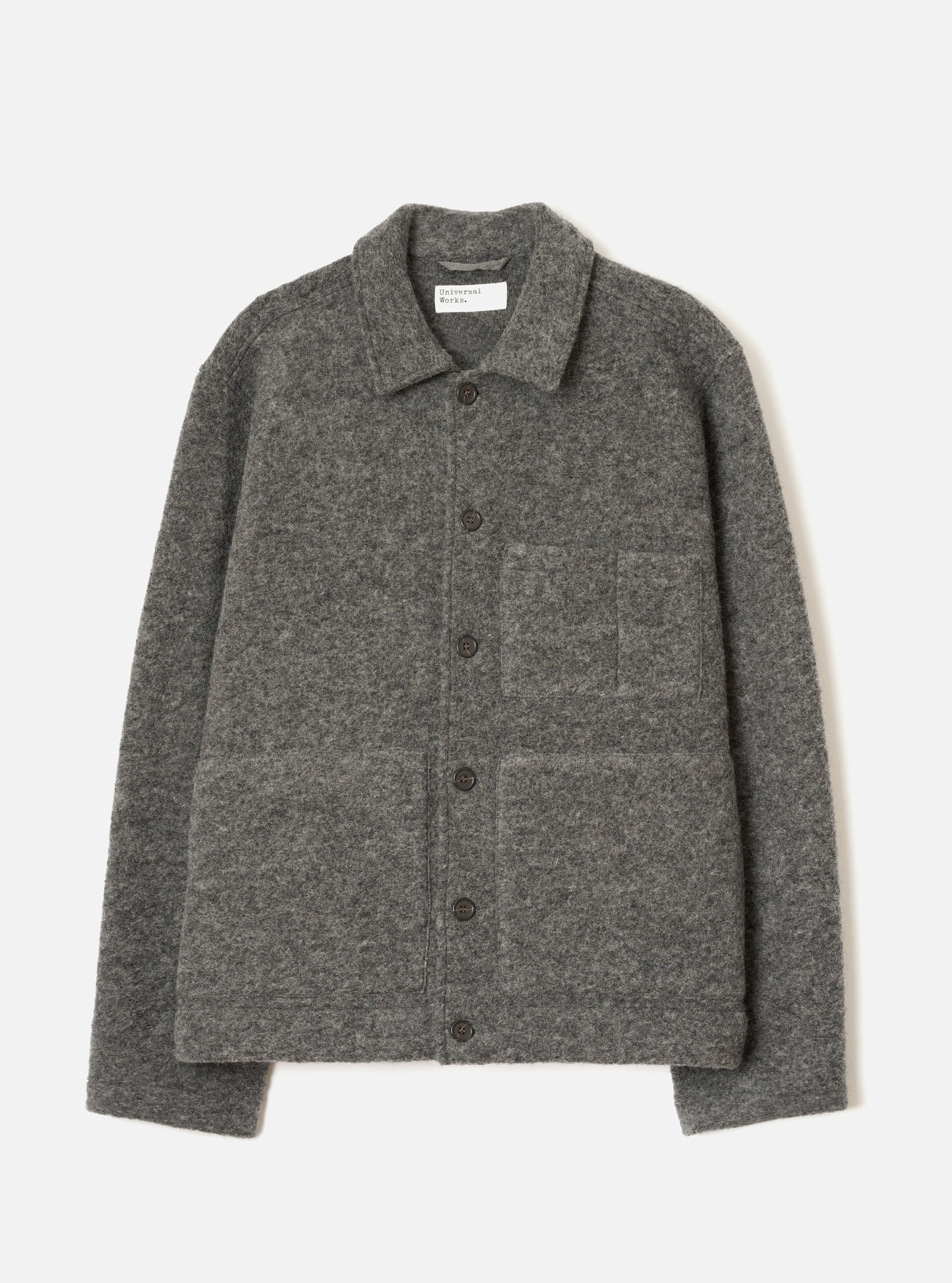 Grey marl wool fleece uniform jacket laid flat on a light grey seamless backdrop. Spread collar with a Universal Works woven label at the neckline. Five dark buttons run down the centre front placket. One chest patch pocket and two large lower patch pockets. Full-length sleeves with plain cuffs. Textured boiled wool fleece fabric throughout.