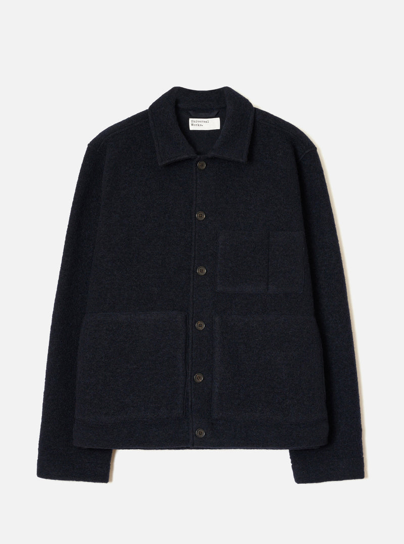 Navy wool fleece uniform jacket laid flat on a light grey seamless backdrop. Features a spread collar, five dark horn buttons down the centre front, two large patch pockets on the chest and lower front, and a ribbed hem and cuffs. The textured fleece has a dense, looped surface throughout.