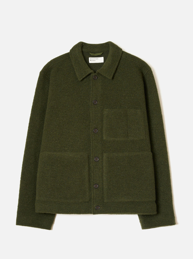 Olive wool fleece uniform jacket laid flat on a light grey studio backdrop. Features a pointed collar, five dark buttons down the centre front, one chest patch pocket and two large lower patch pockets. Ribbed cuffs and a straight hem are visible. A Universal Works woven label sits inside the collar.