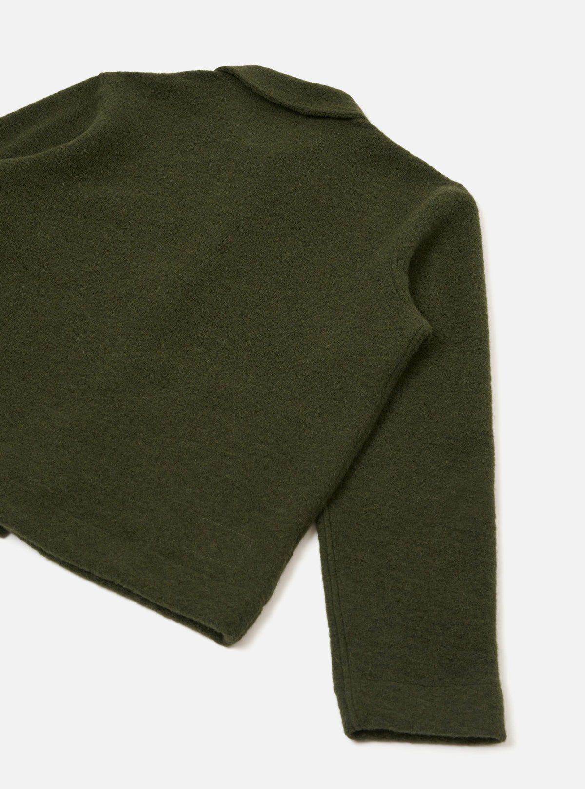 Flat lay of an olive wool fleece uniform jacket on a white studio backdrop. The shot is cropped to show the back and one full sleeve. The boiled wool fleece has a dense, slightly napped texture. A small collar tab is visible at the top. The sleeve has a clean, unfinished-style cuff with no buttons or ribbing.