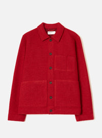 Scarlet wool fleece chore jacket laid flat on a plain white studio backdrop. Features a point collar, six dark horn buttons down the centre front, one chest patch pocket and two large lower patch pockets. Boiled wool fleece texture throughout. Universal Works woven label visible at the neck.