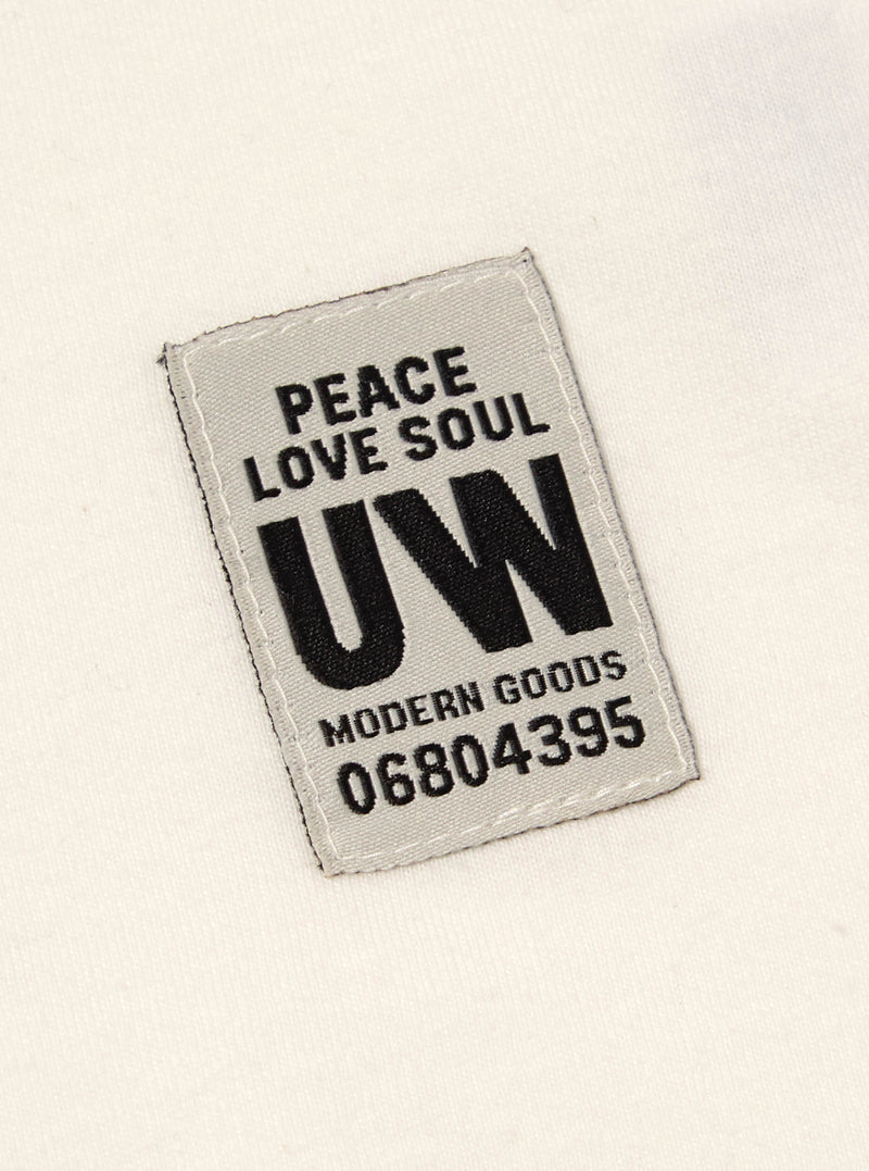 Close up of the label on the Ecru Single Jersey Core Tee. The label is gray with black text. The tee is ecru.