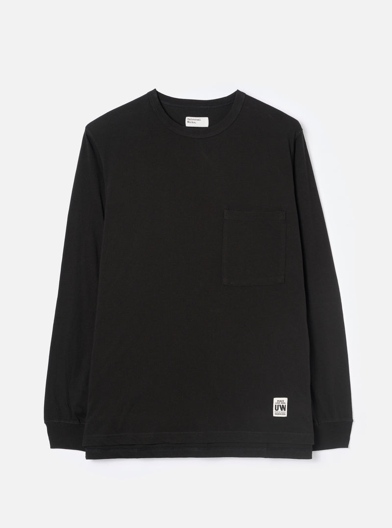 Black long-sleeve jersey T-shirt laid flat on a light grey studio backdrop. Crew neck with a visible Universal Works woven label at the back neck. Single chest patch pocket on the left breast. Ribbed cuffs at the wrists. Small branded UW woven badge at the lower right hem. Plain smooth fabric throughout.