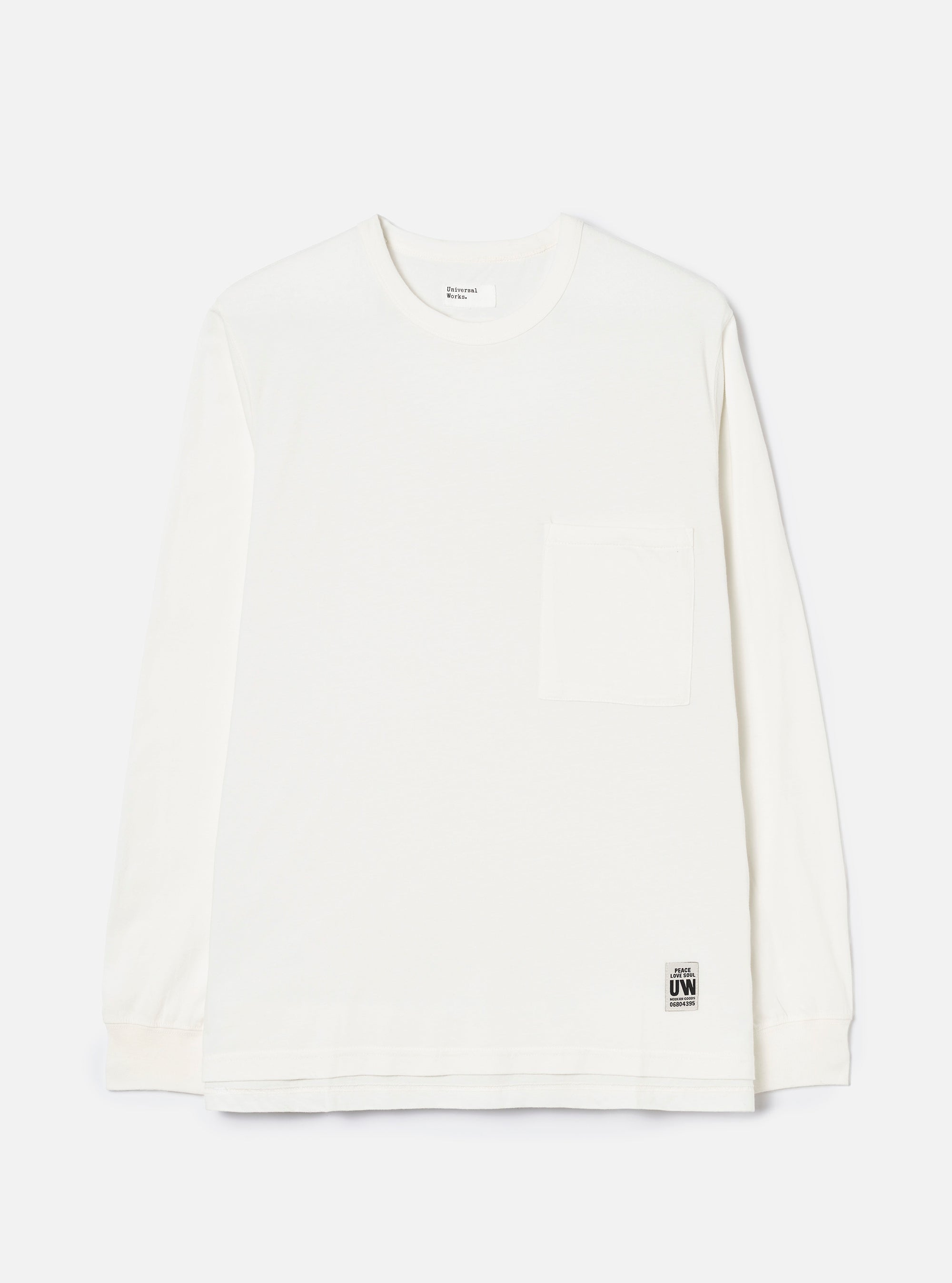 Ecru long-sleeve pocket tee in single jersey cotton, shot flat on a light grey seamless backdrop. Features a crew neck, one chest patch pocket, and ribbed cuffs. A Universal Works woven label sits at the interior neck and a small branded UW tab is stitched at the lower hem.