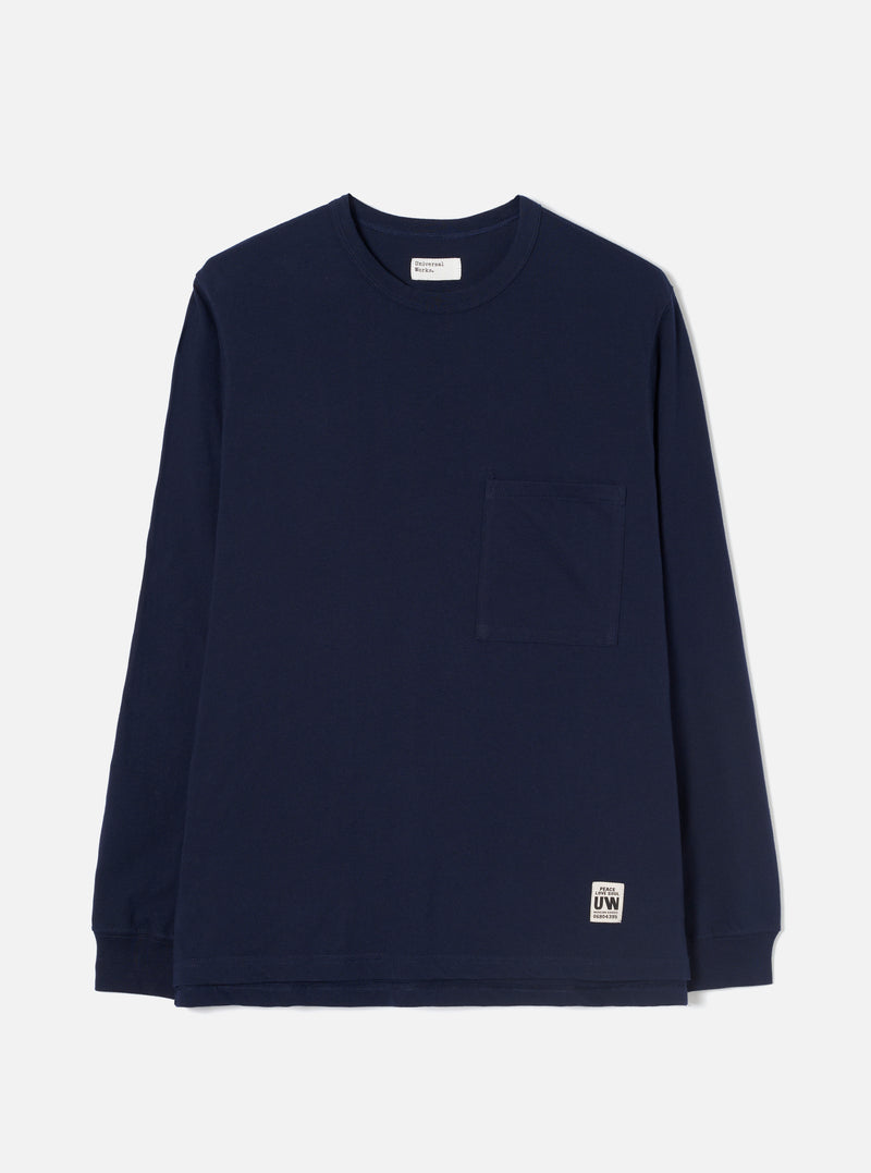 Navy long-sleeve cotton jersey T-shirt laid flat on a light grey seamless backdrop. Features a ribbed crew neck, a single patch chest pocket, and ribbed cuffs. A woven brand label sits at the interior neck and a small printed UW logo tab is sewn at the lower hem. Plain, smooth fabric with no pattern.
