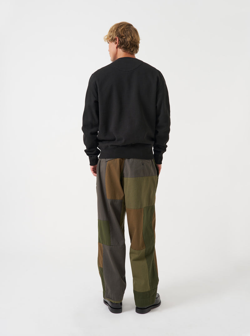 Rear view of a model wearing the Black Brush Back Sweat Core Sweatshirt against a plain light background. The image displays the back of the black cotton crewneck sweatshirt, showcasing its relaxed fit and ribbed bottom hem.