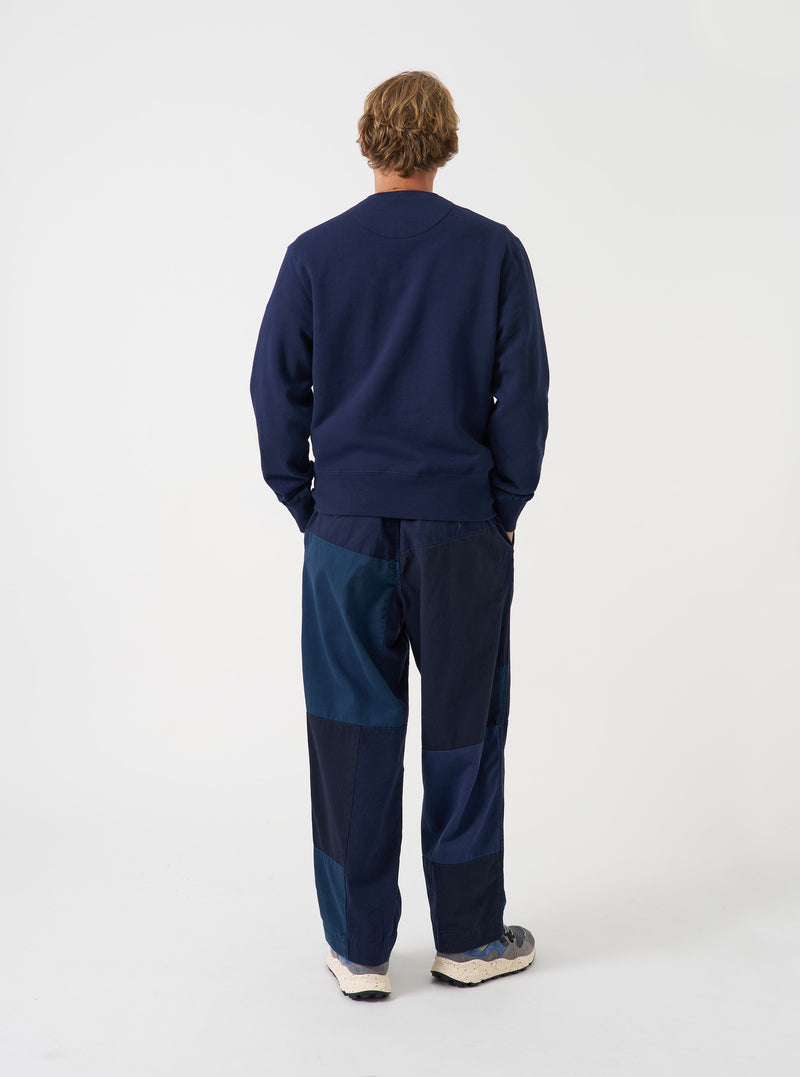 Angled view of a model wearing the Navy Brush Back Sweat Core Sweatshirt in a plain studio setting. The shot demonstrates the garment fit from the side, highlighting the sleeve length and soft brushed cotton texture.