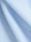 Close-up of the Sky Blue Oxford Daybrook Shirt fabric. The light blue woven material is softly draped, showcasing the texture and color of the shirt.