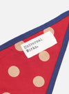 Close-up of the Red Bold Dot Print Rayon Scout Scarf on a white background. The scarf is red with tan dots and a navy blue trim. A white tag with "Universal Works." is visible.