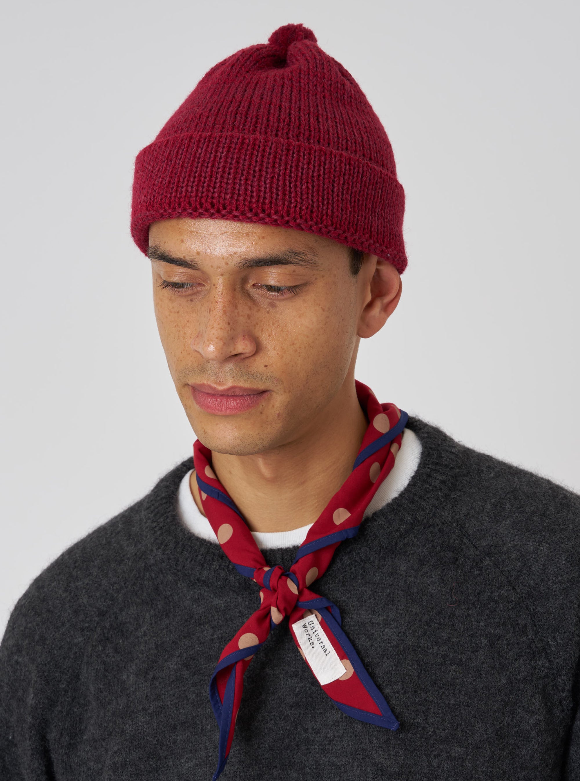 A model wears a Red Bold Dot Print Rayon Scout Scarf tied around his neck. The scarf is red with tan dots and blue trim, against a plain white background.
