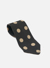 Close-up of a Black Bold Dot Print Rayon Tie on a white surface. The tie features large tan polka dots and is made of soft rayon fabric.