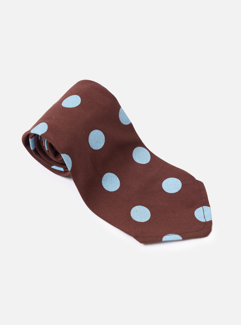 The Brown Bold Dot Print Rayon Tie is shown from the back as a flat lay against a plain white background. The image highlights the construction of the tie, including the keeper loop and the finished tip. The brown rayon fabric features a prominent white bold dot print throughout.