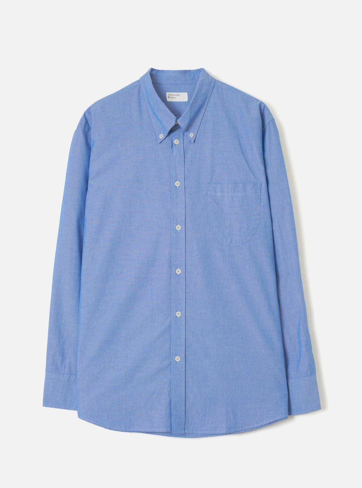 Blue Prince Chambray Daybrook Shirt laid flat on a light grey studio backdrop. The long-sleeve shirt features a point collar, full-length button placket, chest patch pocket, and buttoned cuffs.