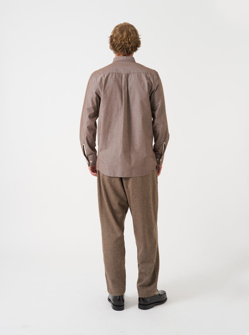 Back view of a male model wearing the Brown Prince Chambray Daybrook Shirt against a plain light grey backdrop. The long-sleeve cotton shirt has a classic button-down fit with a smooth back yoke.