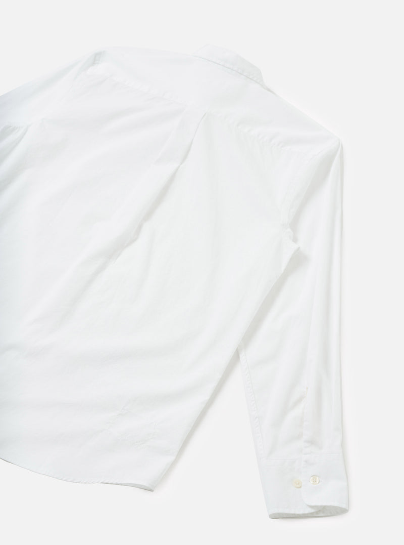 The White Prince Chambray Daybrook Shirt is laid flat on a light grey studio background, shot from above. The rear view shows a small pointed collar, a fine chambray weave, and a long sleeve extending with a cuff featuring two white buttons.