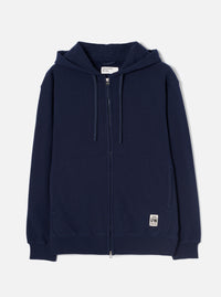 Navy brushback fleece zip-through hoodie laid flat on a white studio backdrop. Full-length silver metal zip, hood with fabric drawcords, two lower patch pockets, ribbed cuffs and hem. Small woven UW brand label at lower right. Universal Works neck label visible inside the hood.