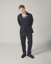 Studio shot of a model wearing a navy suit and Navy Twill Military Chino pants. The background is a plain grey.
