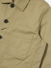 Close-up of the Sand Twill Bakers Jacket, showcasing its sand-colored twill fabric, button details, and pocket. Shot on a white background.