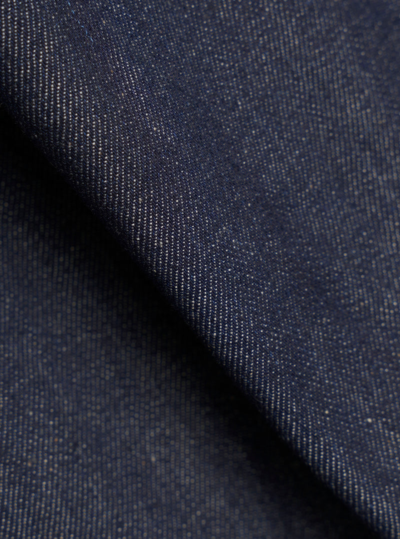 Fabric swatch detail of the Indigo 13oz Selvedge Denim Trucker Jacket against a plain backdrop, highlighting the deep indigo dye, rugged twill weave, and textured finish of the denim.