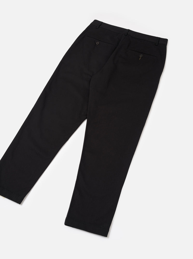 Back view of the Black Twill Military Chino trousers set against a neutral off-white background. Highlights the rear buttoned welt pockets, waistband construction, and clean tailored silhouette.